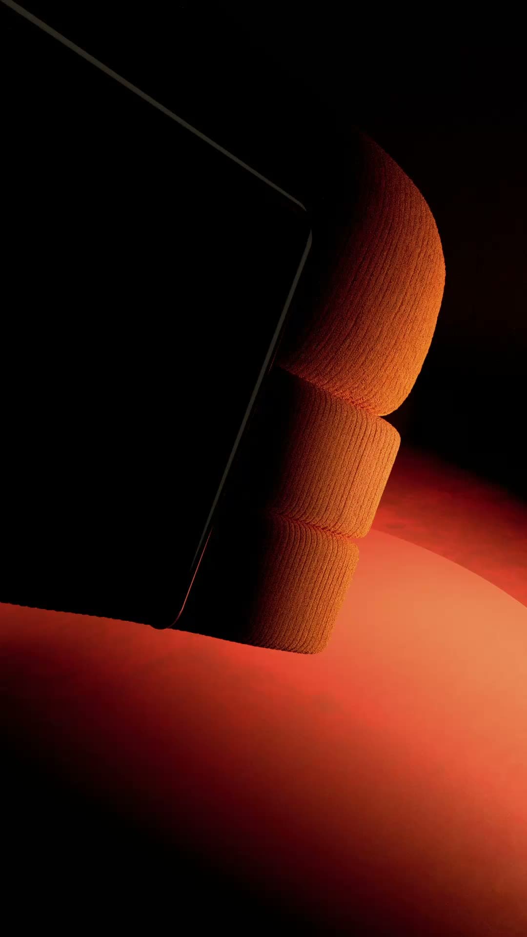 The TEDDY sofa in orange corduroy, turning slowly against a dark backdrop